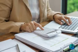 Person using a calculator and laptop to manage financial control.