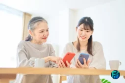 Two women from different generations discussing intergenerational financial planning on their smartphones.