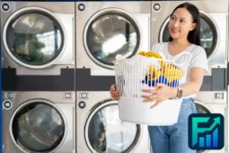 Woman holding a full laundry basket in a laundromat, representing the concept of laundry savings through cost-effective washing routines.