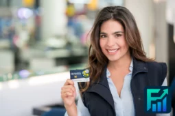 Smiling woman holding a rewards card at a store counter, illustrating Reward Programs.