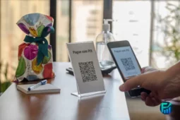 A person using a smartphone to scan a QR code for a Pix payment at a counter.