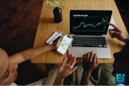 AI Applications in Finance displayed on laptop and smartphone while two people review charts and trading options.