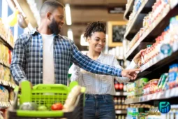 Couple shopping in a grocery store and comparing products, representing grocery inflation and ways to save money on everyday food expenses.
