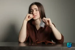 Worried woman holding a credit card while thinking about personal loans vs credit cards.