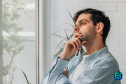 A person sitting by a window, deep in thought while reflecting on upcoming credit decisions.