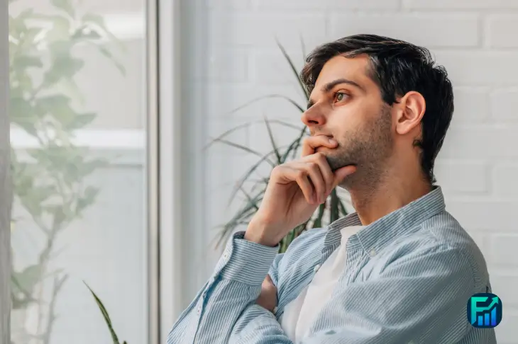 A person sitting by a window, deep in thought while reflecting on upcoming credit decisions.