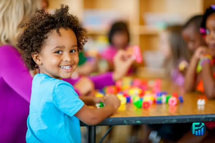 Smiling child playing with colourful toys in a classroom, symbolising support provided by Child Benefits.