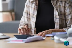 Person reviewing bills and using a calculator at a desk, illustrating a bank fee waiver.
