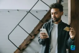 Man looking at his phone while holding a card, reviewing his EBT benefits.