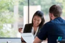 Two people discussing paperwork during a meeting about debt consolidation loans.