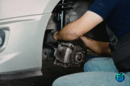Mechanic repairing a car brake system, representing concerns about mechanic overcharging.