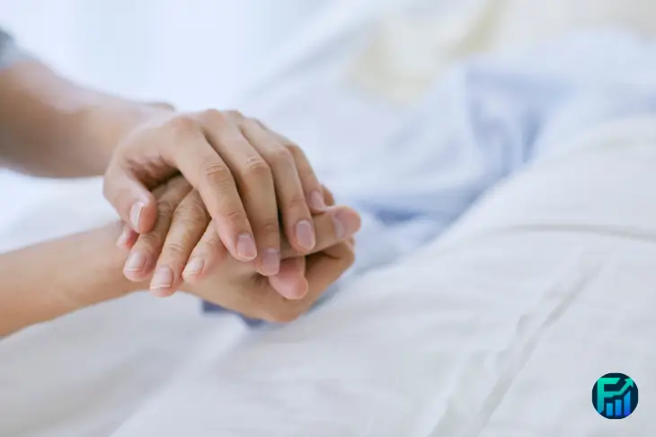 Hands gently holding a patient’s hand in a hospital bed, representing Charity Care support.