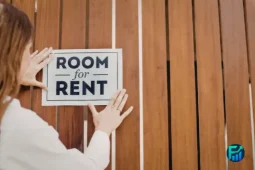 Person placing a “Room for Rent” sign on a wooden fence, illustrating renter rights and housing options.