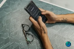 Person using AI to save money on a smartphone while organizing a household budget.