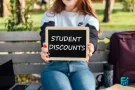 Student holding a Student Discounts sign outdoors.